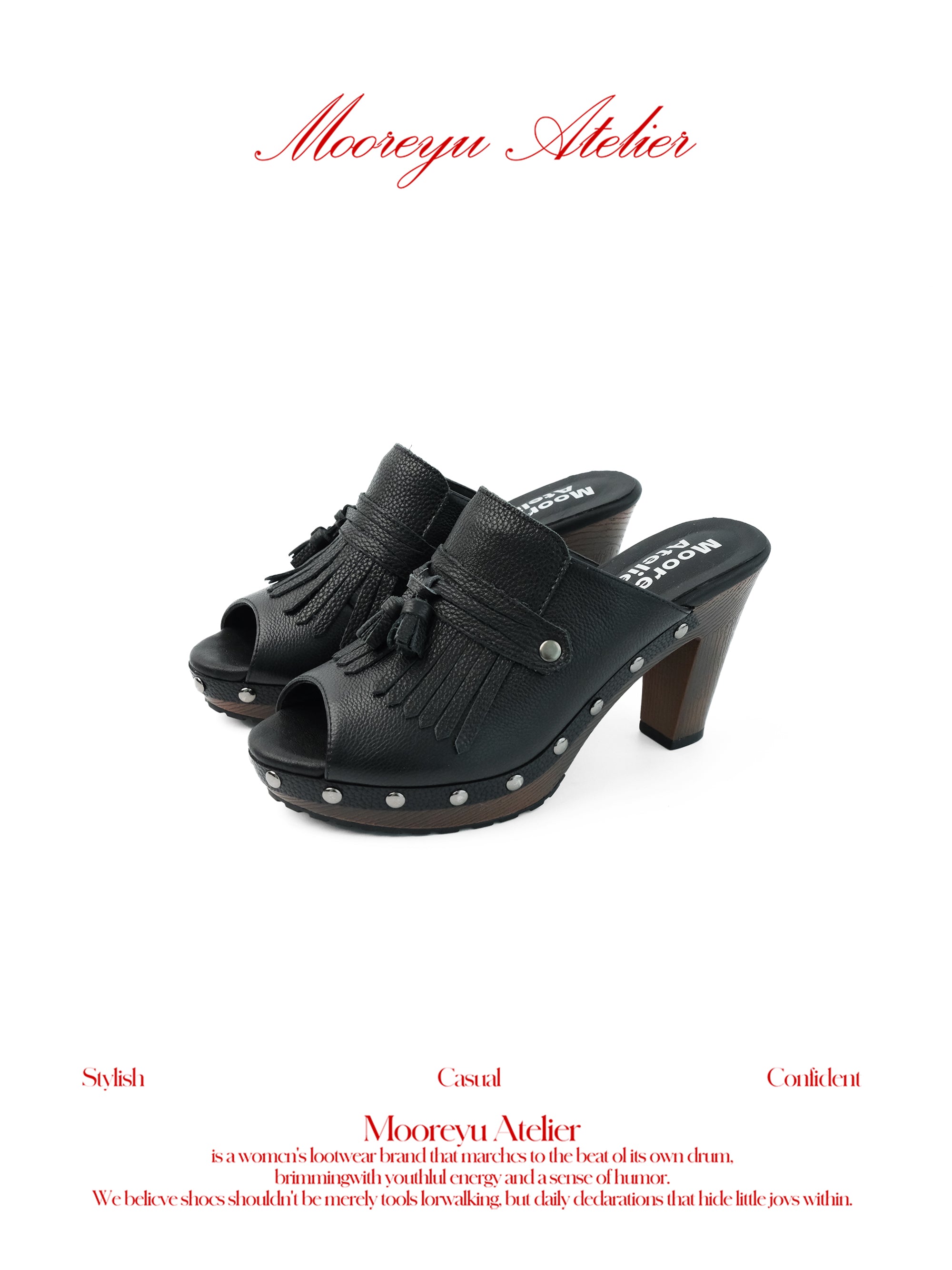White background MOOREYU ATELIER solid black pebbled full grain leather mule clogs, peep toe leather fringe tassels & surrounding silver studs, 10cm faux wood grain platform block heels studio shot