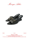 White background studio shot of MOOREYU ATELIER distressed dark grey full grain leather mule slides, pointed toe eyelet fringe leather bow, 7.9cm curved wedge heel
