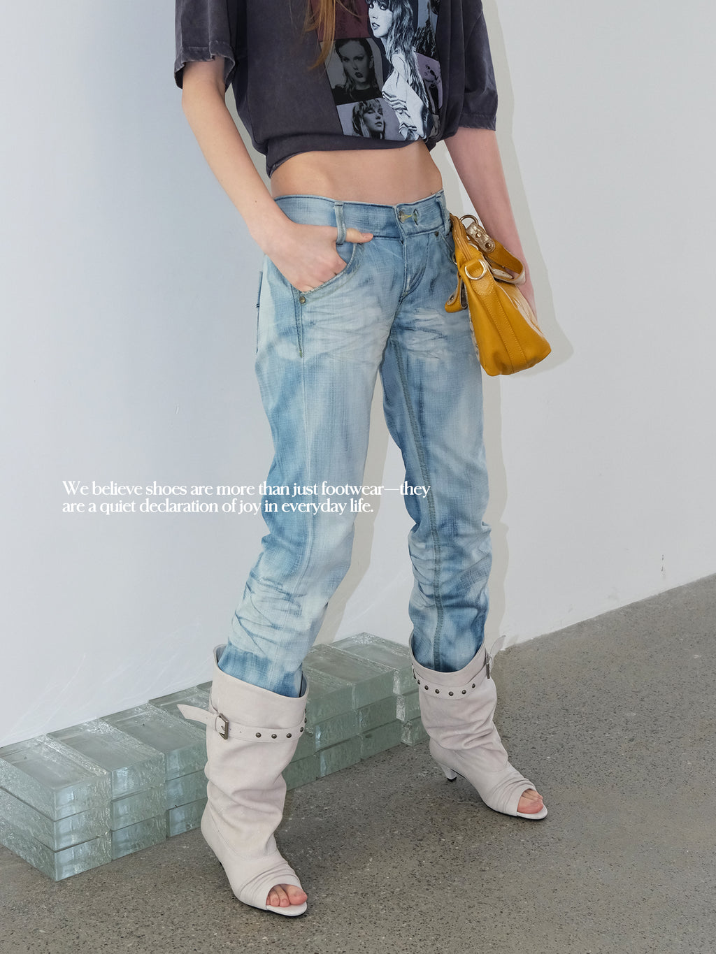 Model in vintage cropped graphic tee & light blue jeans, off-white slouch peep toe knee high leather boots, minimalist indoor studio setting