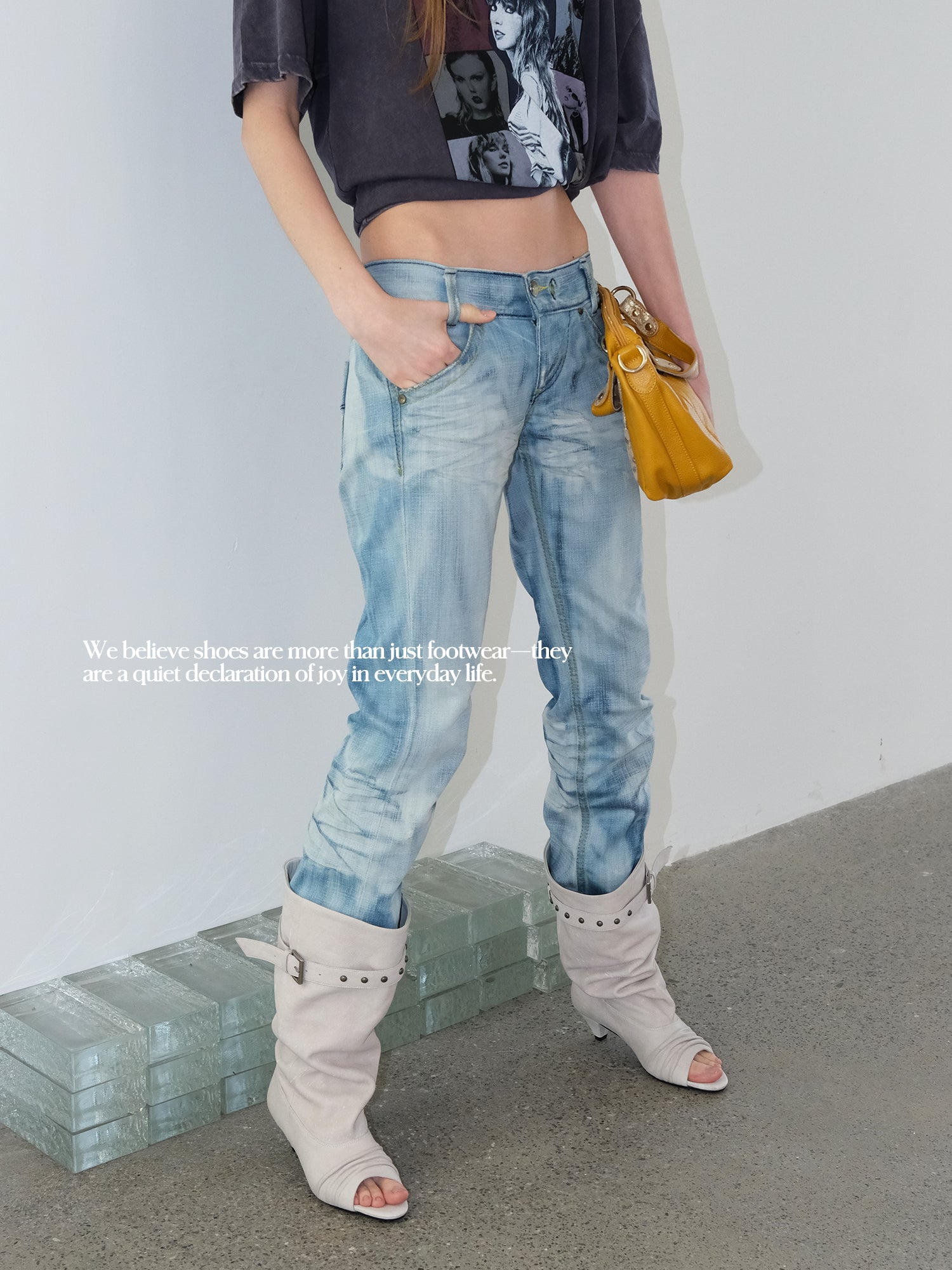 Model in vintage cropped graphic tee & light blue jeans, off-white slouch peep toe knee high leather boots, minimalist indoor studio setting
