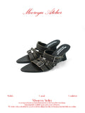 White background MOOREYU ATELIER distressed dark grey full grain leather mule slides, pointed toe multi buckle stud straps, 7.9cm curved wedge heel studio shot