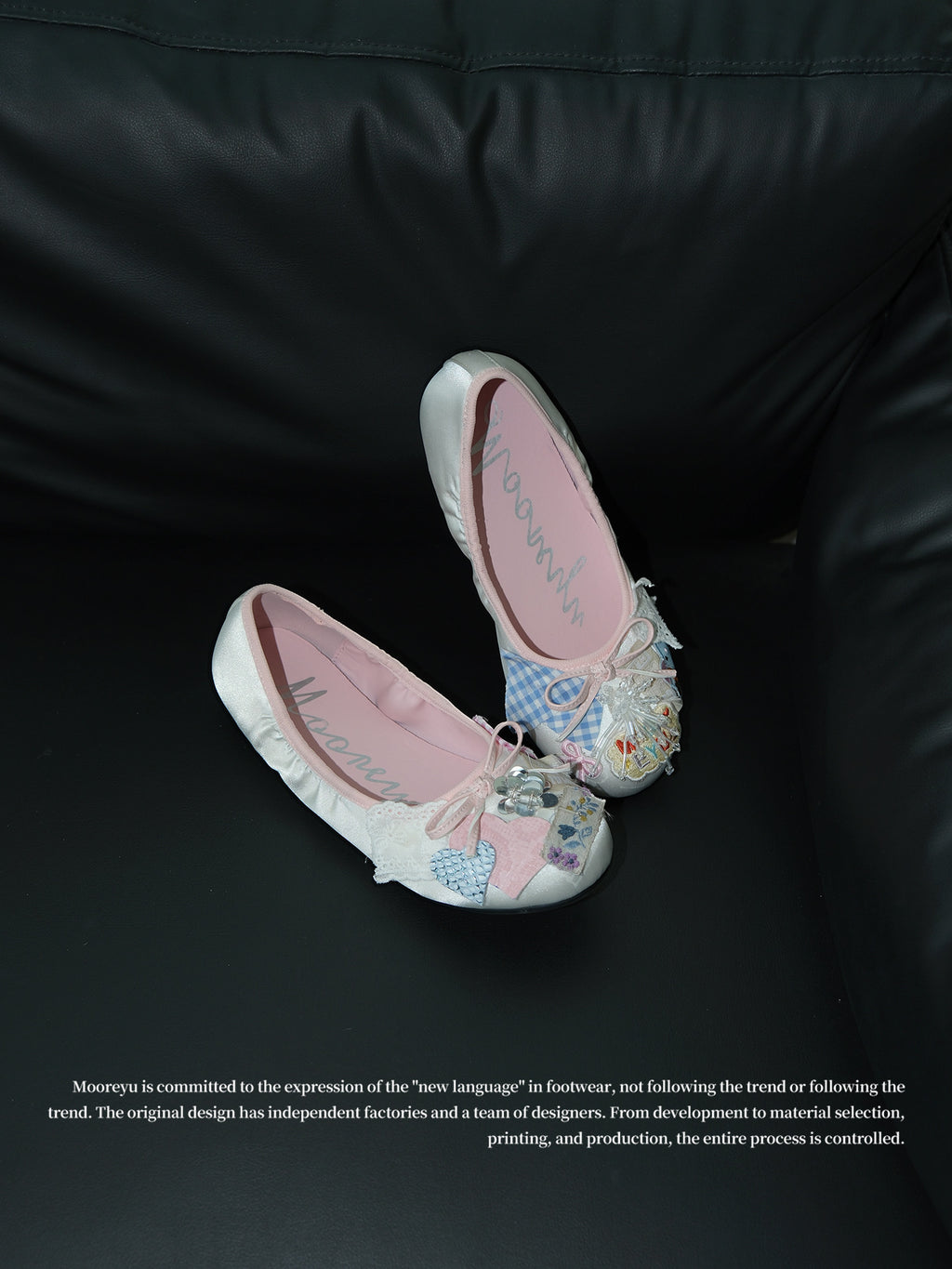 Two pink satin ballet flats with heart embroidery and plaid patch decor placed on black leather sofa, vintage coquette shoe studio shot